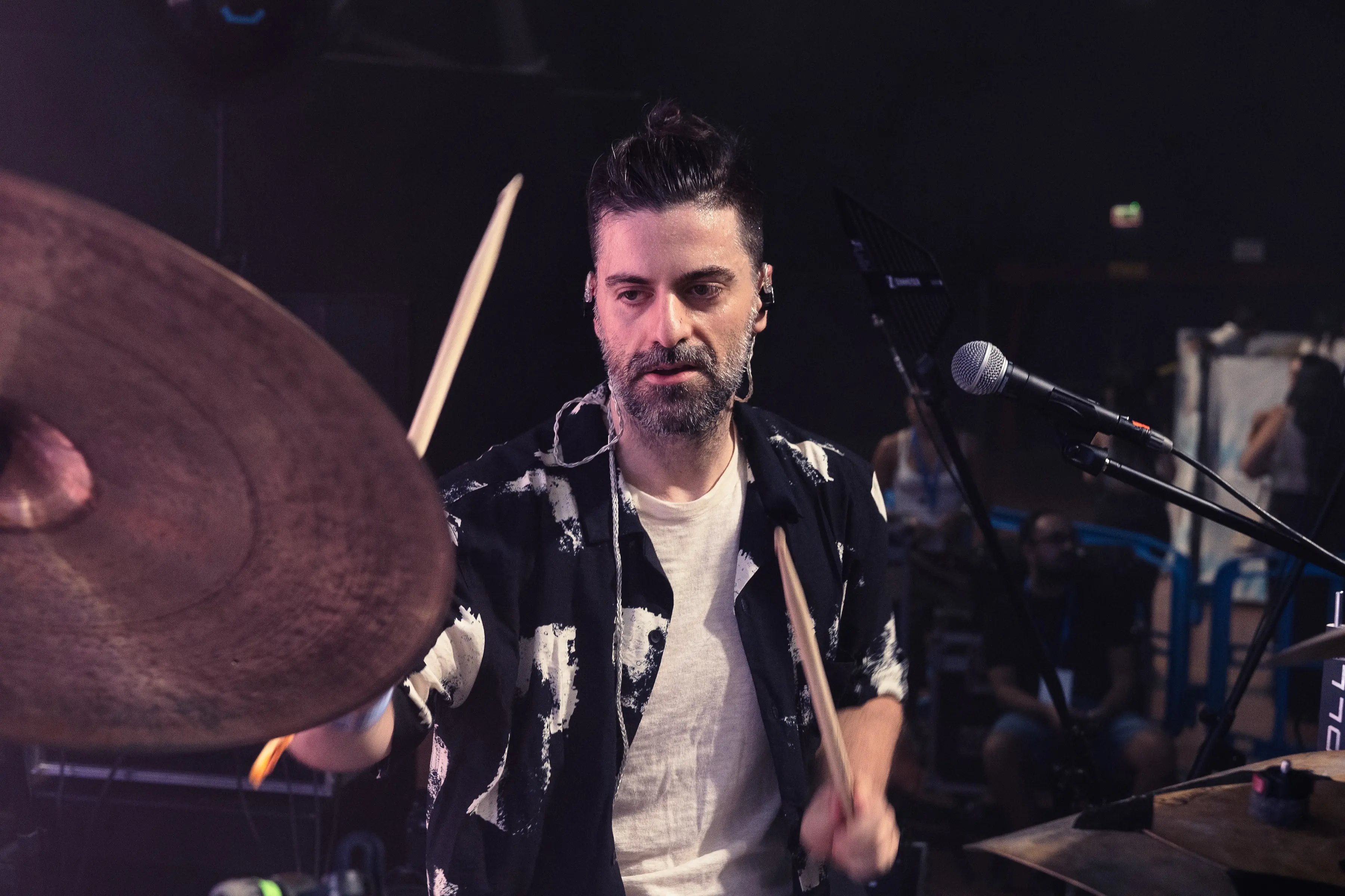 Drummer mid-performance with a cymbal in the foreground