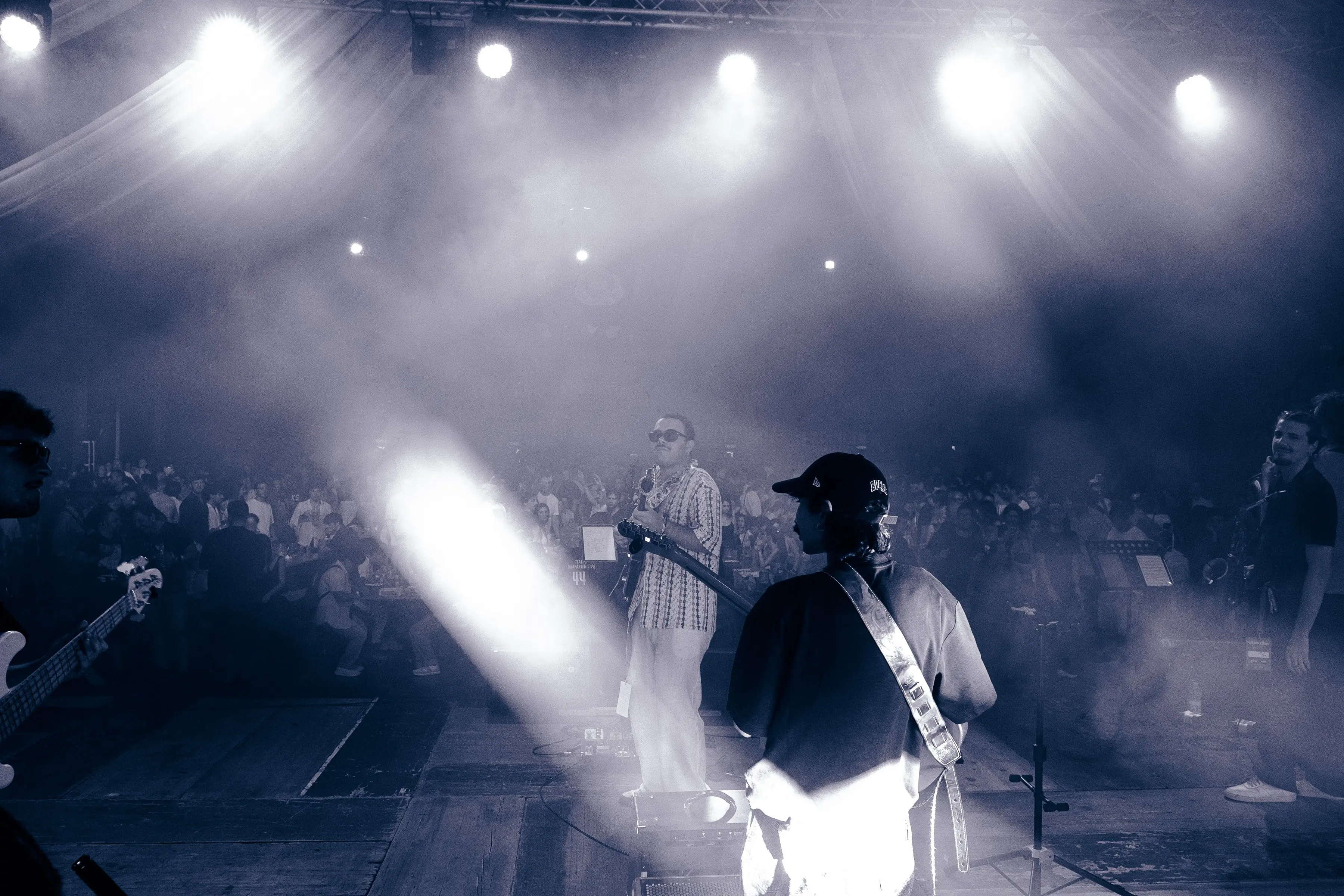 Band performing on a smoky stage as spotlights cut through the haze over the crowd