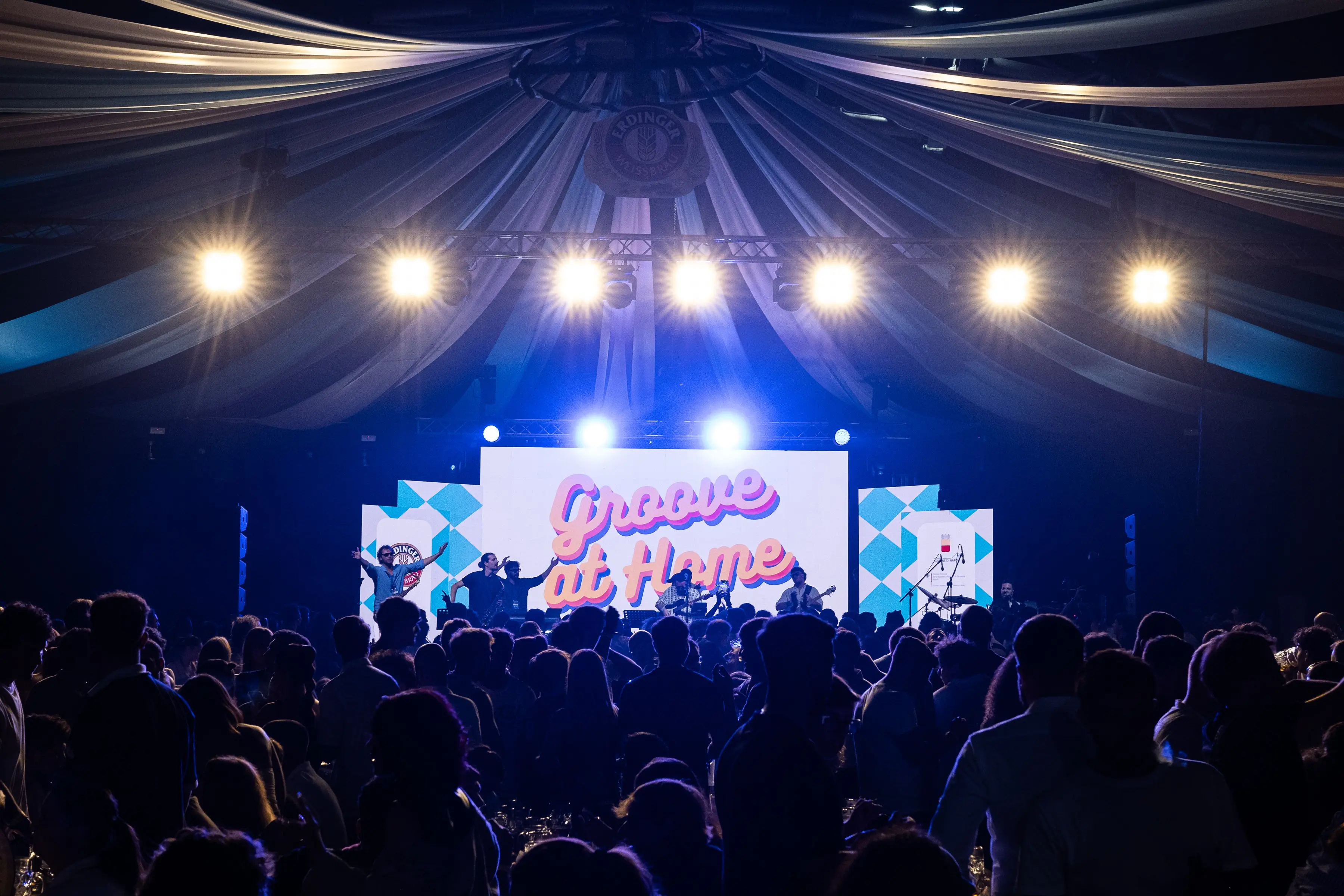 Wide shot of the stage and cheering crowd under warm golden lighting